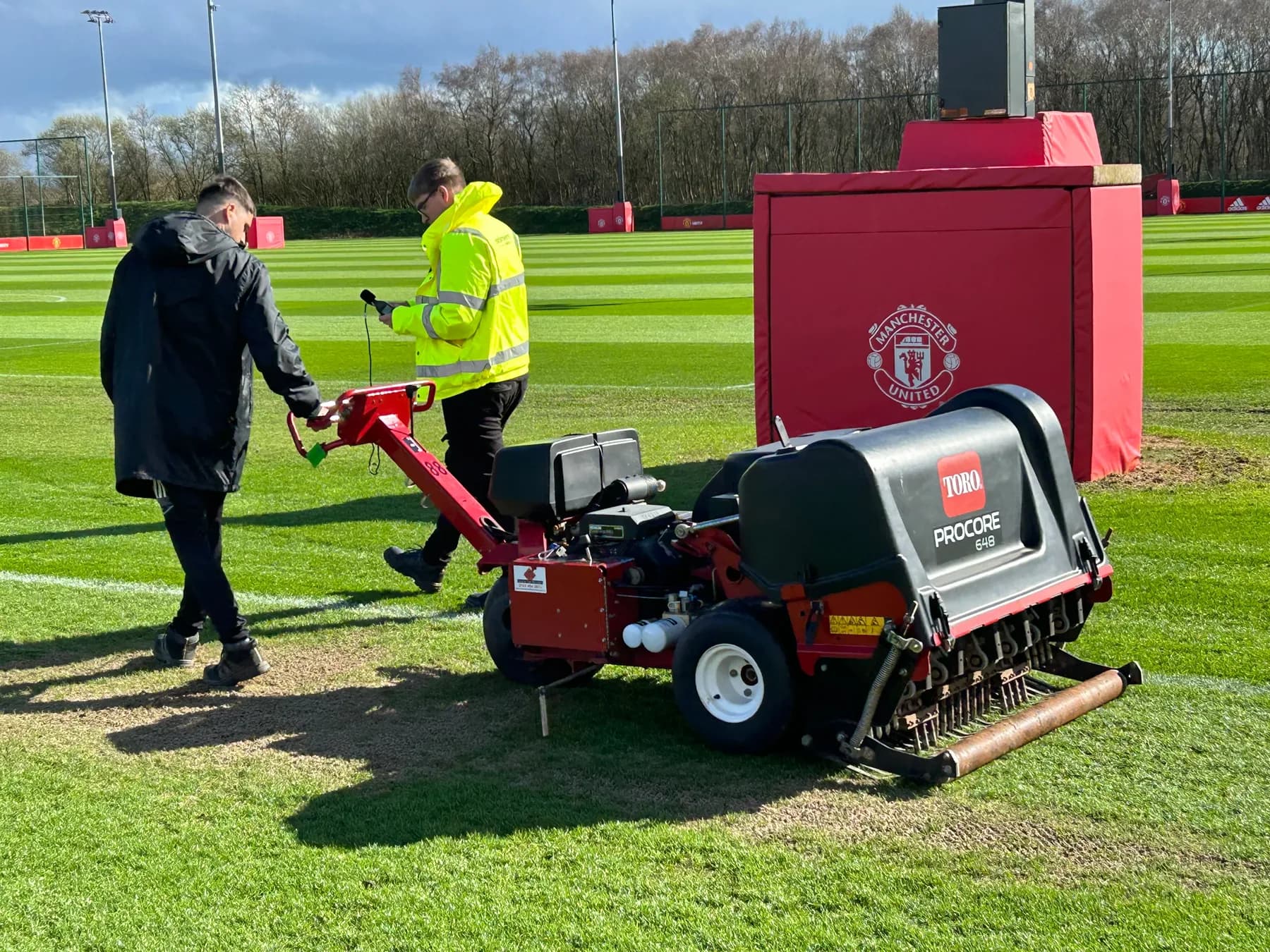 Earlsmere engineer measuring hand-arm vibration on a pedestrian corer during on-site testing at a professional football training ground